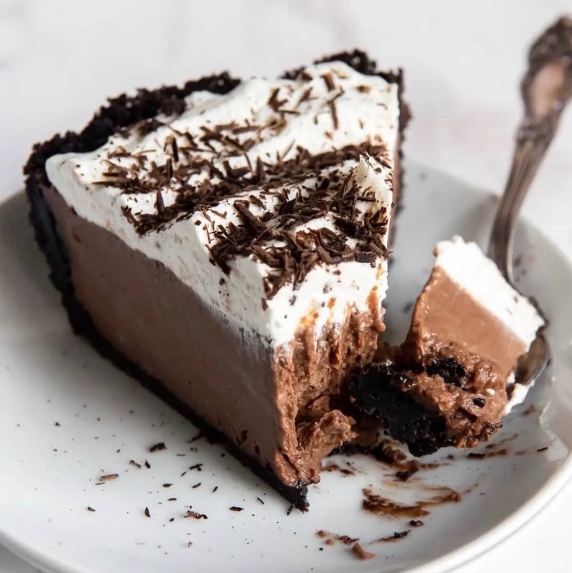 A slice of chocolate cream pie with whipped cream and chocolate shavings.